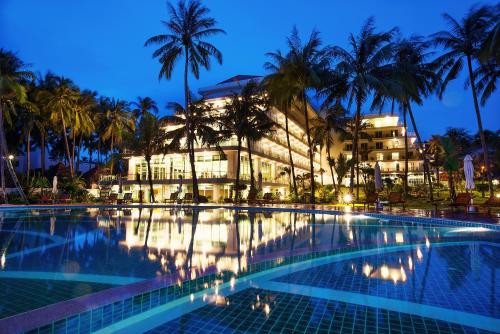 a hotel with a swimming pool in front of a building at Muong Thanh Holiday Muine Hotel in Mui Ne