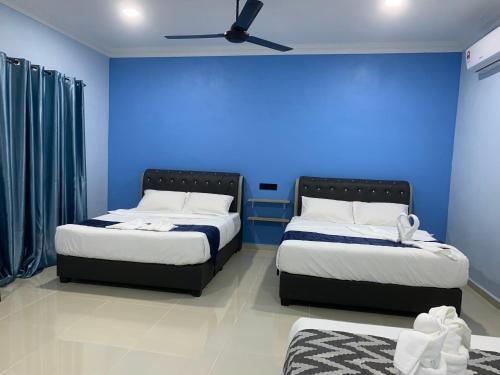2 camas en una habitación con una pared azul en VILLA TASIK TONGKANG KELI LANGKAWI en Kuah