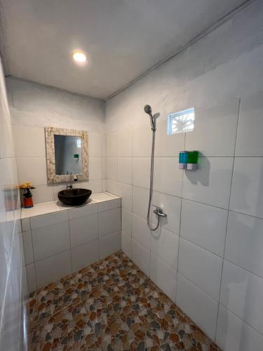 a bathroom with a shower with a sink and a mirror at Bukit Catu Bungalows in Kintamani