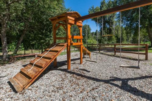 a wooden playground with a swing and a slide at Solar Selvana - Casas de montaña in Villa La Angostura