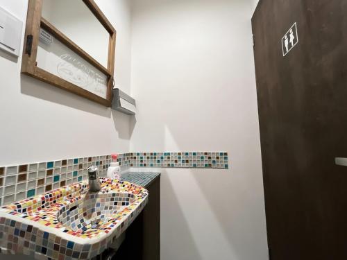 a bathroom with a mosaic sink with a mirror at 古民家ゲストハウス ナマケモノ in Ōno