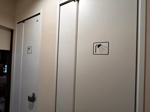 a white door with a sign on it at 古民家ゲストハウス ナマケモノ in Ōno
