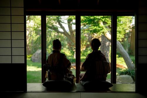 two people sitting in front of a window looking outside at Machi no Odoriba in Kanazawa