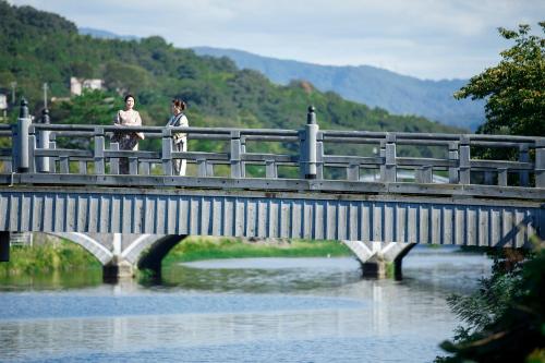 two people walking on a bridge over a river at Machi no Odoriba in Kanazawa