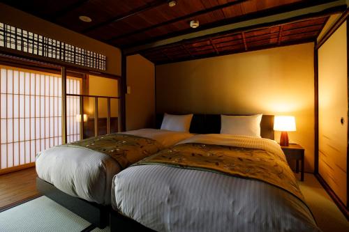 a bedroom with two beds and a large window at Machi no Odoriba in Kanazawa