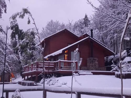 a log cabin in the snow with the door open at Solar Selvana - Casas de montaña in Villa La Angostura