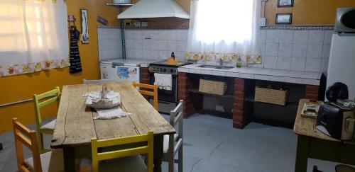 y cocina con mesa de madera, sillas y fogones. en El Trébol Casa de Campo en Naicó