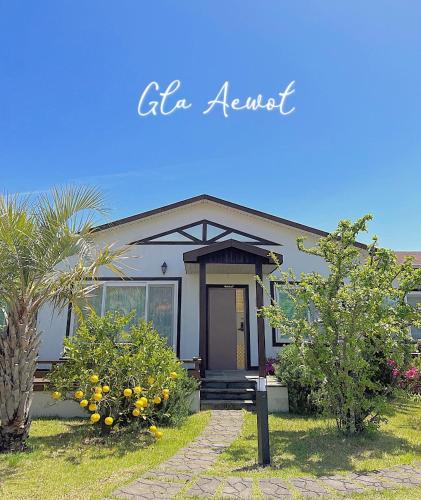 a house with trees and flowers in front of it at Gla Aewol in Jeju