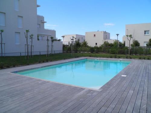- une piscine d'eau bleue sur une terrasse en bois dans l'établissement Appartement 2P avec piscine, proche plage et commerces, parking inclus - Sète - FR-1-338-5, à Sète