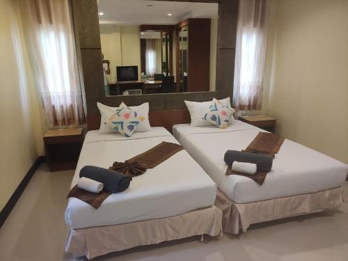 Dos camas en una habitación de hotel con toallas. en Baan Thara Guesthouse, en Ao Nang Beach