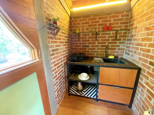 cocina pequeña con fregadero y pared de ladrillo en Comfortable Wood House second floor and attic, en Kuta Lombok