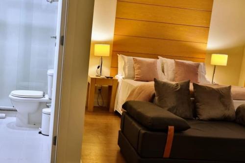1 dormitorio con cama con cabecero de madera y sofá en Linda suite em hotel aeroporto de Congonhas, en São Paulo