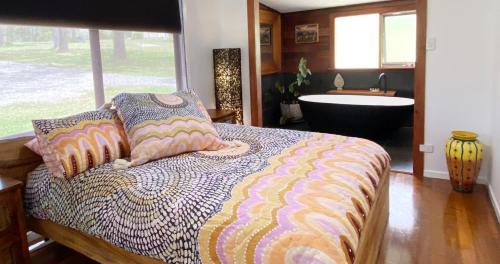 a bedroom with a bed and a tub in a room at Sea Foam Cottage in Corindi