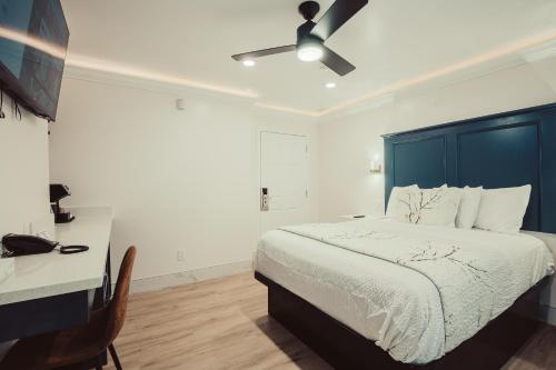 a bedroom with a bed with a blue headboard and a desk at Blufftop Inn & Suites - Wharf/Restaurant District in Morro Bay