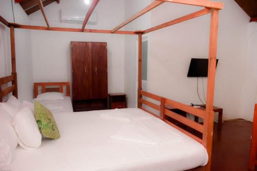 1 dormitorio con 2 literas y TV en Rainforest Chalets - Rainforest Tours,Pool And Ac, en Deniyaya