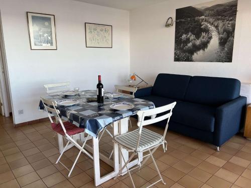 un salon avec une table et un canapé bleu dans l'établissement Charmant 2 pièces proche plage, parking, animaux admis - FR-1-702-47, au Cap d'Agde