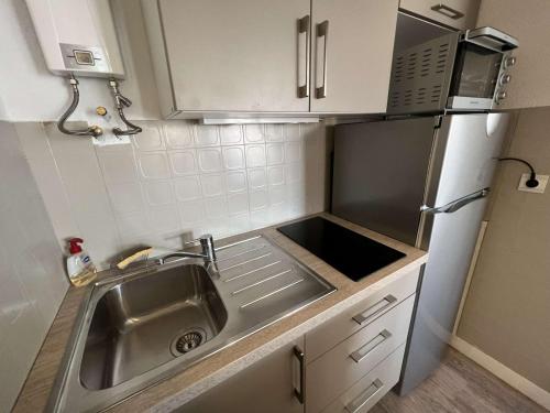 une petite cuisine avec un évier et un micro-ondes dans l'établissement Studio cabine avec ascenseur et parking, proche plage et commerces - FR-1-702-46, au Cap d'Agde