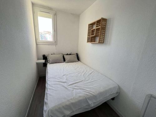 - un petit lit dans une petite chambre avec fenêtre dans l'établissement Studio cabine avec ascenseur et parking, proche plage et commerces - FR-1-702-46, au Cap d'Agde