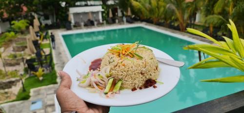 une personne tenant un plat devant une piscine dans l'établissement Lucky Beach Resort, à Trincomalee