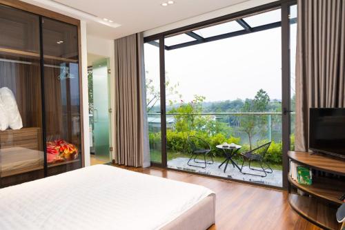 - une chambre avec un lit, une télévision et un balcon dans l'établissement Villa & Resort Đại Lải - 3, à Phúc Yên