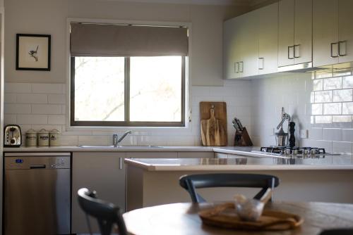 a kitchen with white cabinets and a table and a window at Butmaroo Station in Bungendore