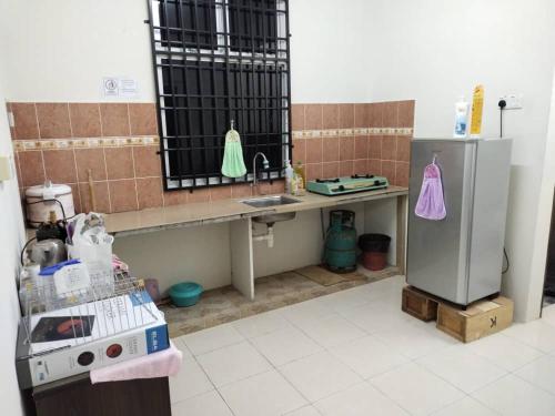 uma cozinha com um balcão, um lavatório e um frigorífico em Sacha Permai Homestay em Baling