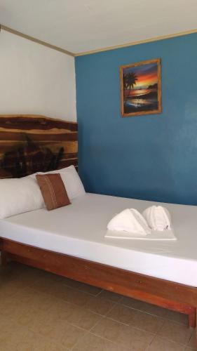 duże łóżko w pokoju z niebieską ścianą w obiekcie SUMMER HOMES BEACH RESORT w mieście Port Barton