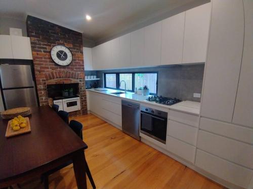 uma cozinha com uma mesa e um relógio na parede em Heritage Cottage in the heart of Bendigo em Bendigo