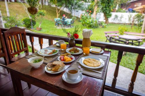 a table with breakfast foods and coffee on a balcony at Villa Chitdara in Luang Prabang