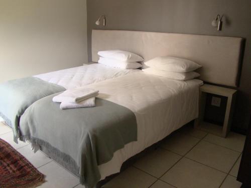Bergliot Guest House في ايدنفيل: غرفة نوم بسرير كبير عليها شراشف ووسائد بيضاء