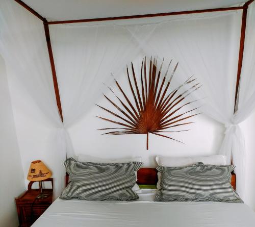 a bedroom with a bed with a headboard and two pillows at Villa Malandy Appart Hôtel Duplex 2 in Nosy Be
