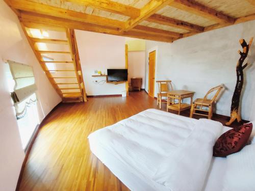 1 dormitorio con 1 cama blanca, mesa y sillas en Cow House, en Jian