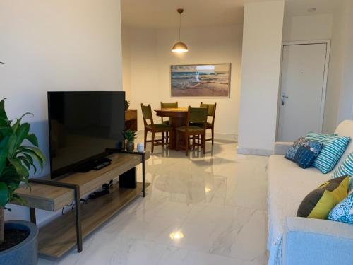 sala de estar con TV y mesa en Apartamento com Suíte, varanda com vista total para o mar de Copacabana, garagem, piscina e sauna, en Río de Janeiro