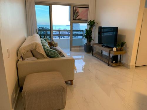 sala de estar con sofá y TV en Apartamento com Suíte, varanda com vista total para o mar de Copacabana, garagem, piscina e sauna, en Río de Janeiro