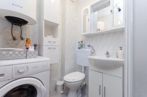 a white bathroom with a washing machine and a sink at Apartment Mare in Vrsar