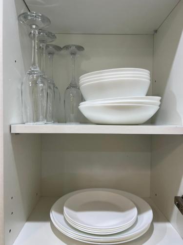 a white shelf with plates and glass bottles at Prisma Apartment in Tallinn