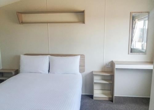 a bedroom with a white bed and a window at St Cyrus Park in Montrose