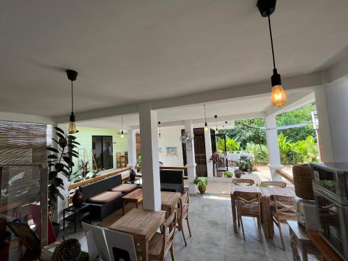 a living room with tables and chairs and windows at Hutch Lodging House in El Nido