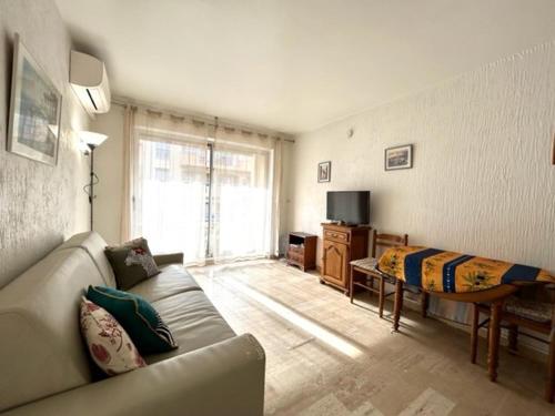 un salon avec un canapé et une télévision dans l'établissement Studio lumineux à 30m de la plage, balcon, clim, commerces à côté - FR-1-226-444, à Sainte-Maxime