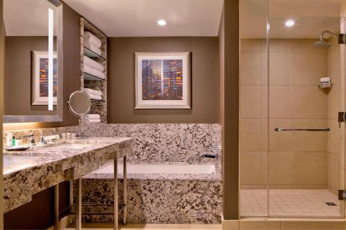 a bathroom with a shower and a tub and a sink at Sheraton New York Times Square Hotel in New York