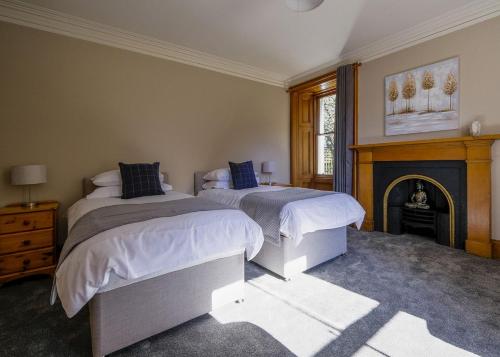 a bedroom with two beds and a fireplace at Gledfield Highland Estate in Culrain