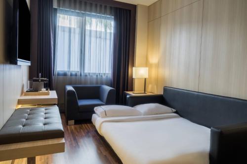 セビリアにあるAC Hotel Ciudad de Sevilla by Marriottのベッド、ソファ、椅子が備わるホテルルームです。