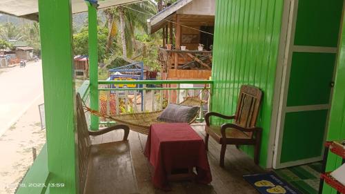 a green house with a hammock on a porch at Ustaris Homestay in Itaytay