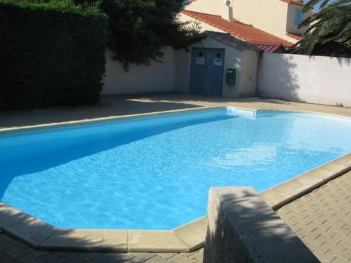 une grande piscine bleue à côté d'un immeuble dans l'établissement Villa Tim avec piscine commune et à deux pas de la plage, à Sainte-Marie-la-Mer