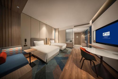 Holiday Inn Express Liaoyuan Economic Dev Zone, an IHG Hotel في Liaoyuan: غرفة فندقية بسرير وتلفزيون بشاشة مسطحة