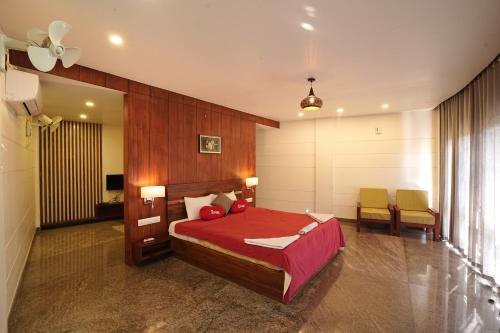 a bedroom with a red bed and a table and chairs at Mayookham in Thirunelli