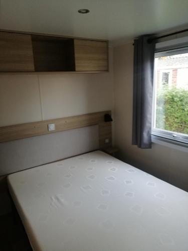 a small bedroom with a bed and a window at MHVACANCES LOUENT PLUSIEURS MOBILHOMES DANS CAMPING 4 ETOILES PROCHE CHATEAUX et ZOO BEAUVAL in Onzain