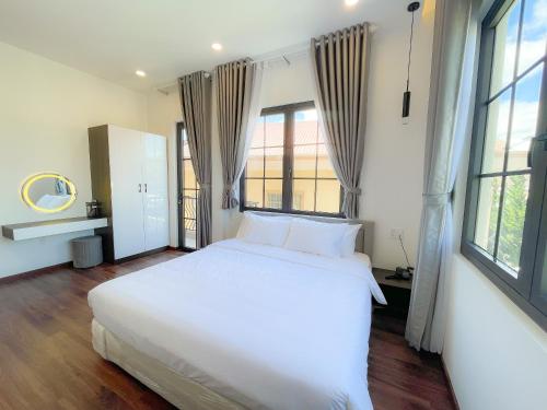 a large white bed in a room with windows at Camellia Villa Hotel in Khu Chi Lăng