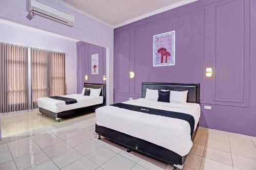 Dormitorio púrpura con 2 camas y pared púrpura en Capital O 92250 Hall & Guesthouse Kowapi Syariah, en Purwokerto