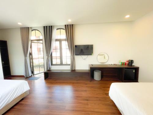 a room with two beds and a desk in it at Camellia Villa Hotel in Khu Chi Lăng